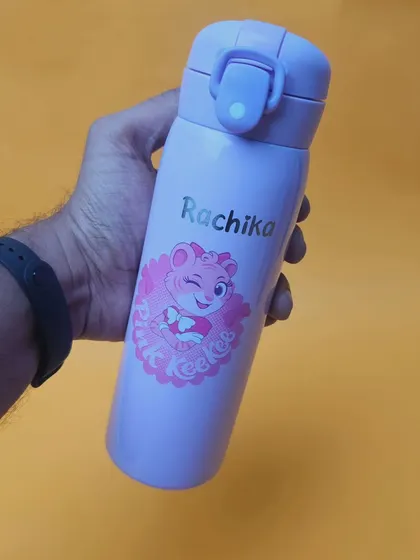 A cute pink-themed bottle for kids, personalized with the name 'Rachika'. These durable stainless steel bottles are perfect for school and make great birthday gifts.