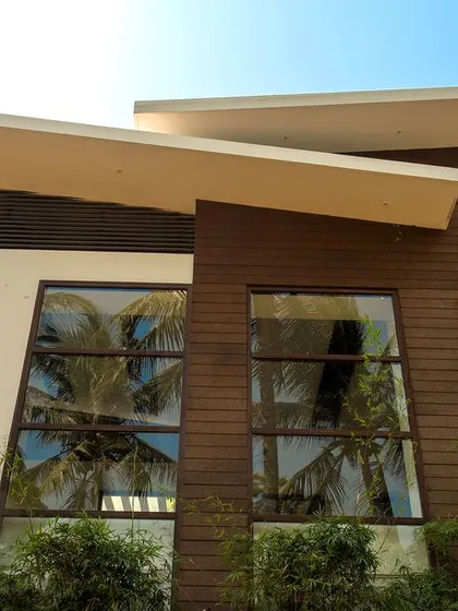 A close-up of the upper facade, showing the sharp lines of the sloped roof and the contrast between the white plaster and the warm wood-clad sections.