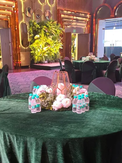 An elegant table setting with a green velvet tablecloth and a simple floral centerpiece, suitable for any upscale celebration.