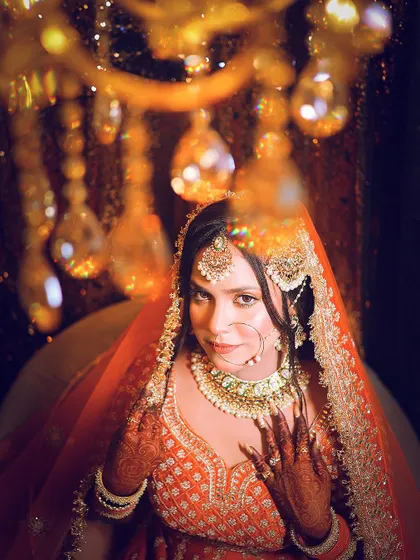 A creative shot looking through the chandelier, framing the bride in a unique and artistic way.