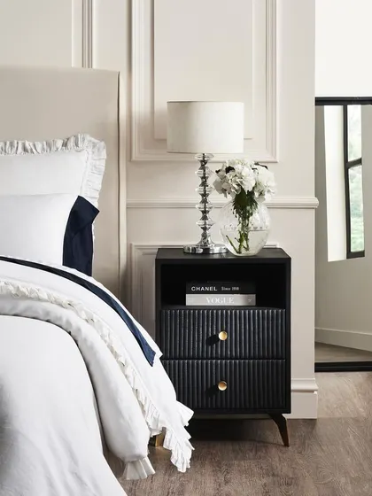 A close-up vignette of the matching nightstand next to a bed. This in-context shot helps customers visualize the piece in their own bedroom.