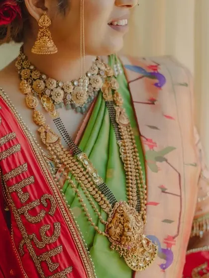 A detailed shot focusing on the bride's exquisite traditional gold jewelry and the custom embroidery on her shawl.