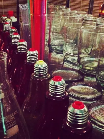Lightbulb-shaped bottles and conical flasks used for serving drinks at a science-themed party. I source unique glassware to perfectly match any event theme.