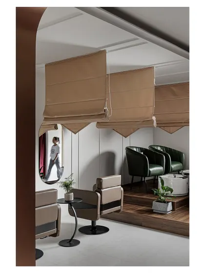 This view showcases the different zones within the salon, from the main styling area to a more private section with raised flooring. The use of mirrors and reflective surfaces enhances the sense of space.