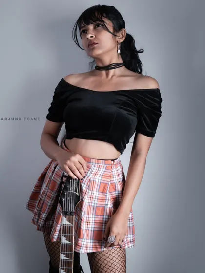 Holding an electric guitar as a prop to enhance the rock-and-roll theme. This pose from the 'Grunge & Glory' series is perfect for music-inspired fashion stories.
