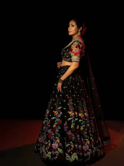 A side profile showing the beautiful flare of the black embroidered lehenga. The placement of the floral motifs is designed to draw the eye upwards, creating a flattering and elegant silhouette.