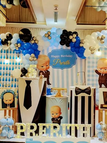 A grand Boss Baby setup in a hotel banquet hall. The decor features multiple character cutouts and a balloon arch in the classic blue, black, and white color scheme.