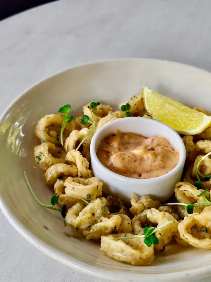 Crispy calamari fritos served with a tangy dipping sauce and a wedge of lime. A classic seaside snack, Granny style.