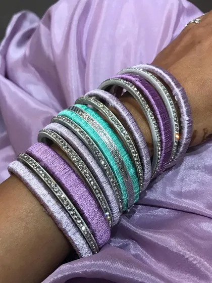 A close-up shot of the handcrafted silk thread bangles. You can see the detail of the thread wrapping and the sparkle of the accent bangles.