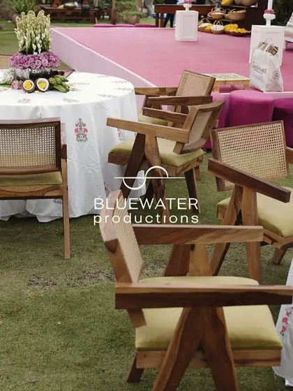 Guest seating with modern wooden chairs and printed tablecloths, set up on the lawn for the Haldi.