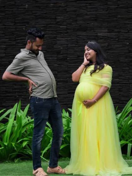 A playful and funny maternity shot where the dad-to-be joins in on the fun. The bright yellow gown adds to the cheerful and lighthearted mood.