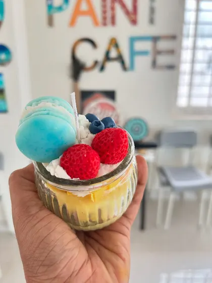 This custom dessert candle features wax strawberries, blueberries, and a light blue macaron.