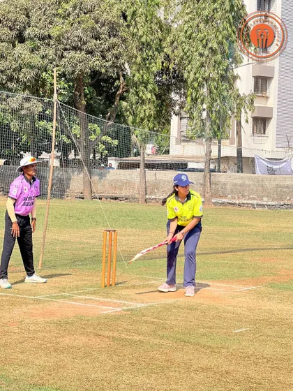 A female batter prepares to face a delivery, demonstrating her batting stance and focus.
