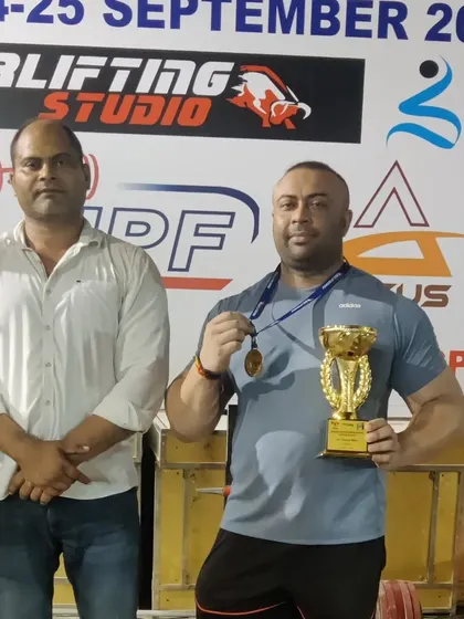 With my coach, holding my gold medal and strong man trophy from the Delhi State Championship.