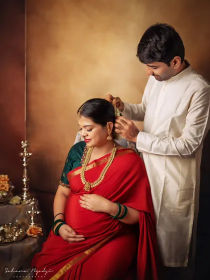 A gesture of love and care. The dad-to-be gently places flowers in his wife's hair, a small, intimate detail that makes this traditional maternity portrait so special.