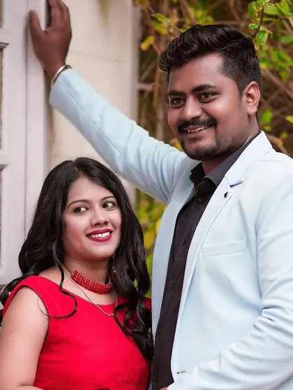 A stylish portrait of a couple posing by a white paned door and green ivy.