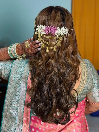 A beautiful hairstyle with open curls and a floral hair accessory, one of the five distinct looks for this bride.