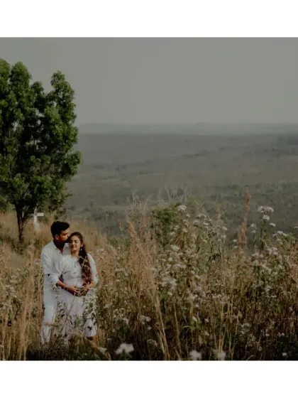 A wide shot of a couple embracing in a field, with a vast, open landscape behind them. It evokes a feeling of peace and endless possibility.