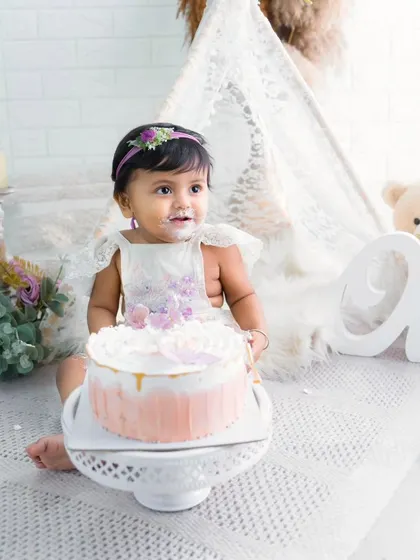 A delicate moment from a boho-chic cake smash session. This little girl is just about to dig into her beautiful first birthday cake.