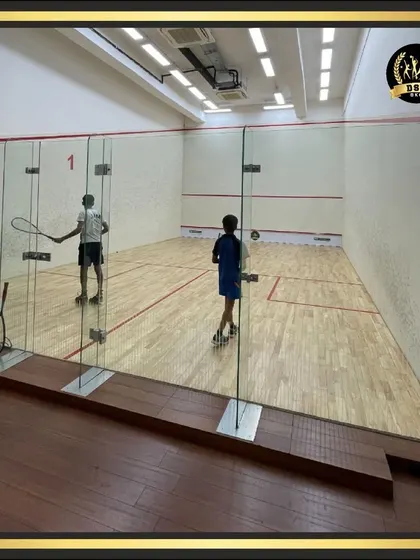 Two players engaged in a fast-paced game of squash, viewed from behind the glass wall. Our courts provide an excellent viewing experience for spectators.