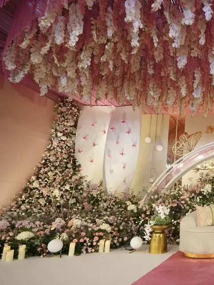 A closer view of the stage seating, surrounded by a lush, overflowing garden of pastel flowers. The design creates a sense of being enveloped by nature, turning a simple seating area into a fantastical photo opportunity.