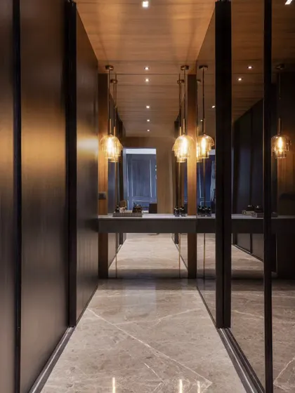 The walk-in closet in the master suite, featuring custom wardrobes and an elegant dressing table. The pendant lights add a warm, ambient glow.