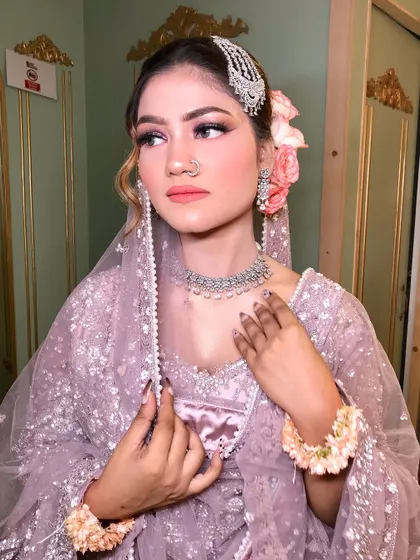 A side view of the pastel purple look, highlighting the fresh flowers in her hair and the delicate nose ring.