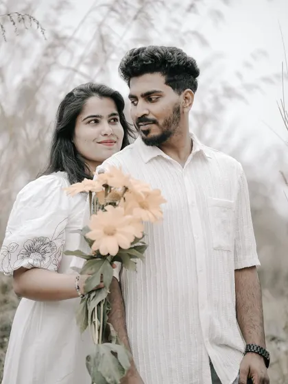 A sweet portrait of a couple in a field, the bride holding a bouquet of yellow flowers, sharing a look.
