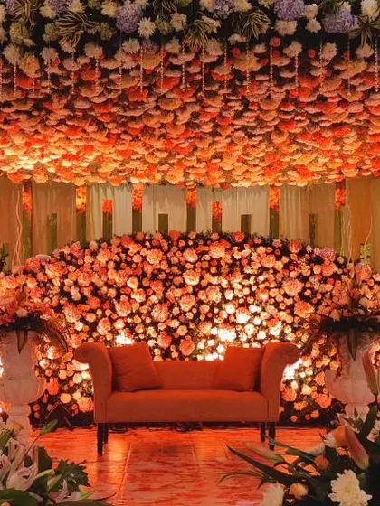 A truly unique stage design featuring a mountain of orange and pink roses. An overhead floral chandelier mirrors the arrangement below, creating a breathtaking paradise of flowers.