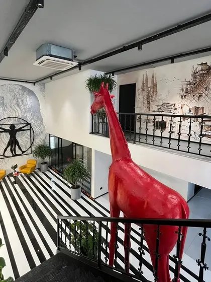 For the Centrix design office, we created several murals to inspire creativity. This view shows two key pieces: a tribute to Leonardo da Vinci and a large-scale architectural montage, with a quirky red giraffe sculpture adding a pop of color.