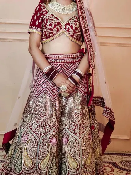 This image shows a bride in a heavy maroon and gold sequined lehenga, paired with a custom white Polki choker set.