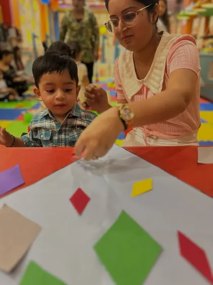 A mother helps her son with a craft, showing the supportive role parents play in our classes.