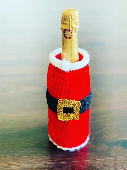 A close-up of the Santa suit bottle cover, showing the crochet texture.