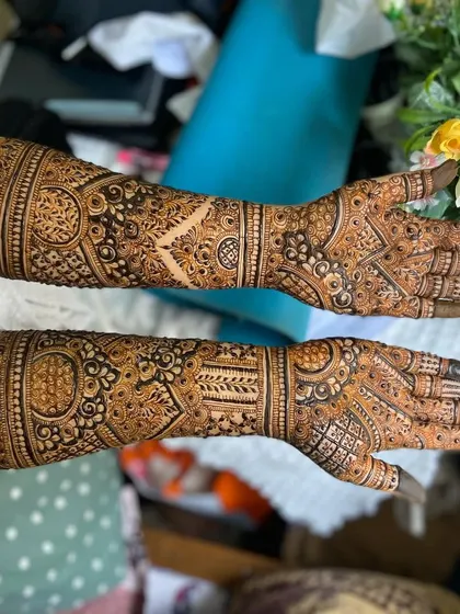 Both arms adorned with heavy bridal henna, ready for the wedding festivities. The patterns are rich and cover the skin completely for a dramatic effect.