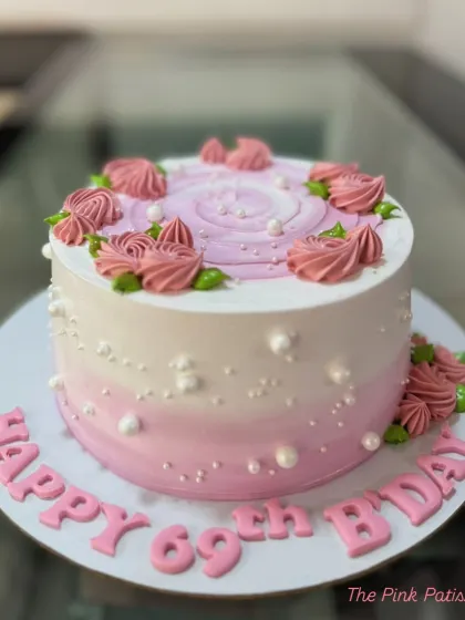 A pretty pink ombre cake for a 69th birthday, decorated with piped roses and delicate pearls.