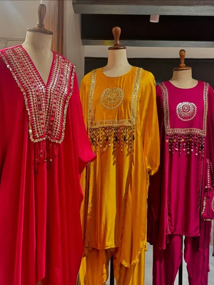 A trio of festive tunics by Prahnaaya in bright red, yellow, and pink, featuring ornate mirror work and tassel details.