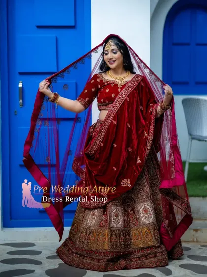The red velvet bridal lehenga is shown here with the dupatta draped over the head, creating a classic bridal pose.