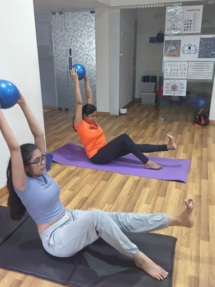 Students use stability balls to perform a variation of Navasana (Boat Pose). The ball adds an element of instability that forces the core muscles to work harder, building deep abdominal strength while maintaining proper form.
