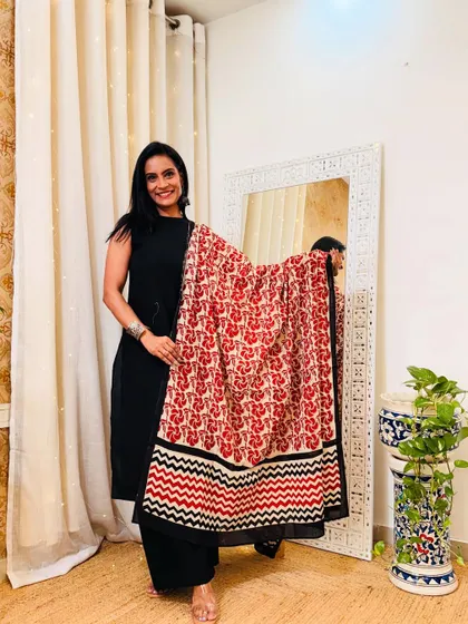 This black suit paired with a red, black, and white printed dupatta is a bold and striking combination. Perfect for making a statement.
