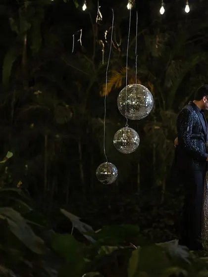 A romantic night portrait of the couple. The hanging disco balls and the lush green background create a unique and magical setting for their reception photos.