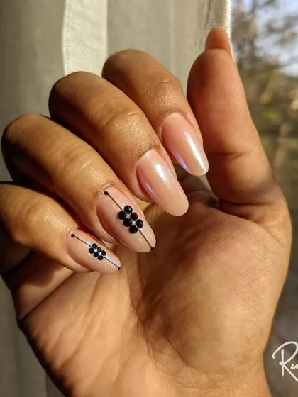 A modern design on a pearlescent nude base. I used black studs and fine lines to create a geometric accent on two nails.