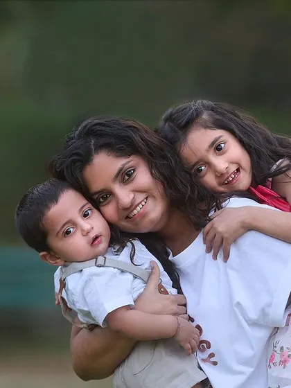 A mother's arms full of love. This portrait beautifully captures the bond between a mom and her two children, a toddler and an infant, in a warm, loving embrace.