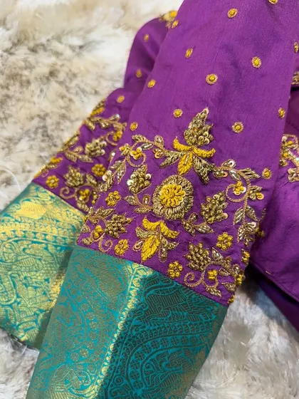 A close-up of the sleeve of the purple and green blouse, showing the detailed zardosi work on the cuff.