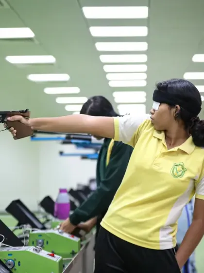 A young athlete takes aim with a pistol at our indoor shooting range. We provide a safe and professional environment for shooters to develop the focus and precision required for their sport.