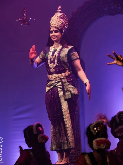 A dancer portraying a goddess, standing tall and serene.