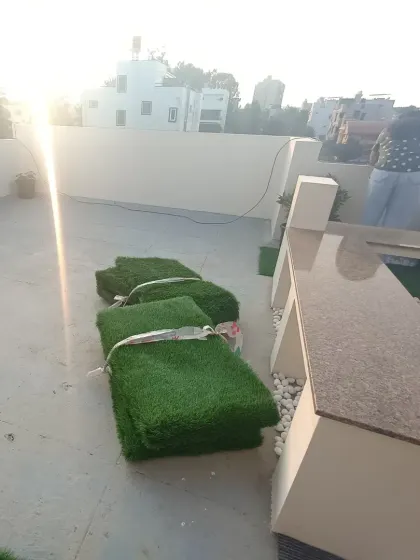 This photo was taken during the installation process, showing the rolls of artificial grass ready to be laid out on the prepared rooftop surface.