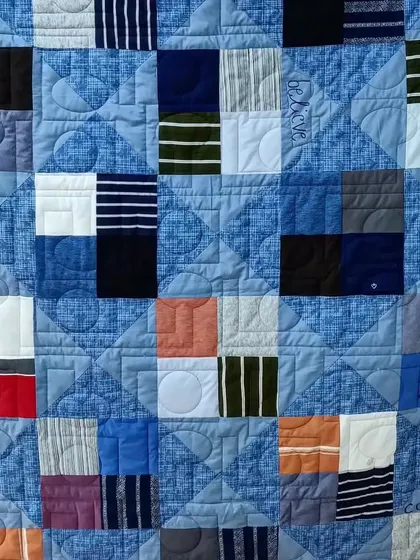 A detailed view of the personalized quilting on a T-shirt memory quilt, with words like "Love" and "Compassion" stitched in.