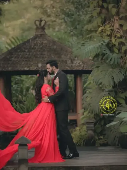 The flowing red fabric of the gown beautifully frames the couple, adding to the romance of this lush, tropical-inspired setting.