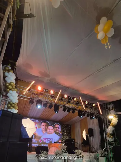 A wider shot of the venue, showing how the lighting rig and stage become the focal point of the entire tented space. The warm yellow and orange lighting creates an inviting and celebratory atmosphere.