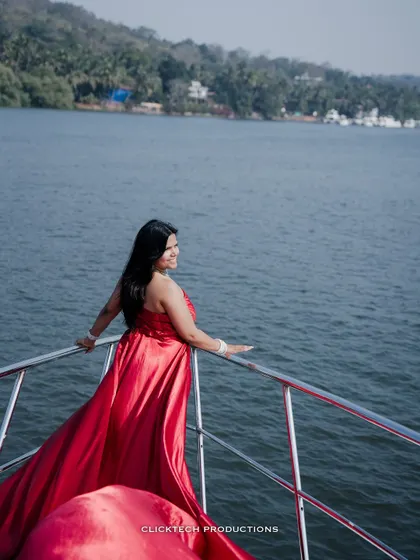 A candid shot of the bride-to-be on a yacht, looking out at the water, her red gown flowing beautifully.